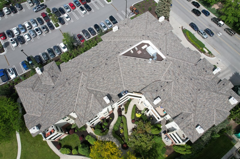 Completed asphalt shingle roof across a multi-unit residential building, seen from directly above