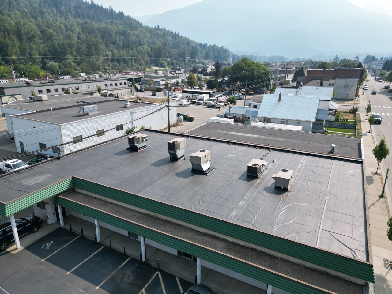 Completed black EPDM membrane roof on a commercial building, mountain town beyond