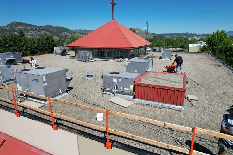 The crew at work on the old gravel roof, guardrail up along the edge, the red pyramid roof beyond