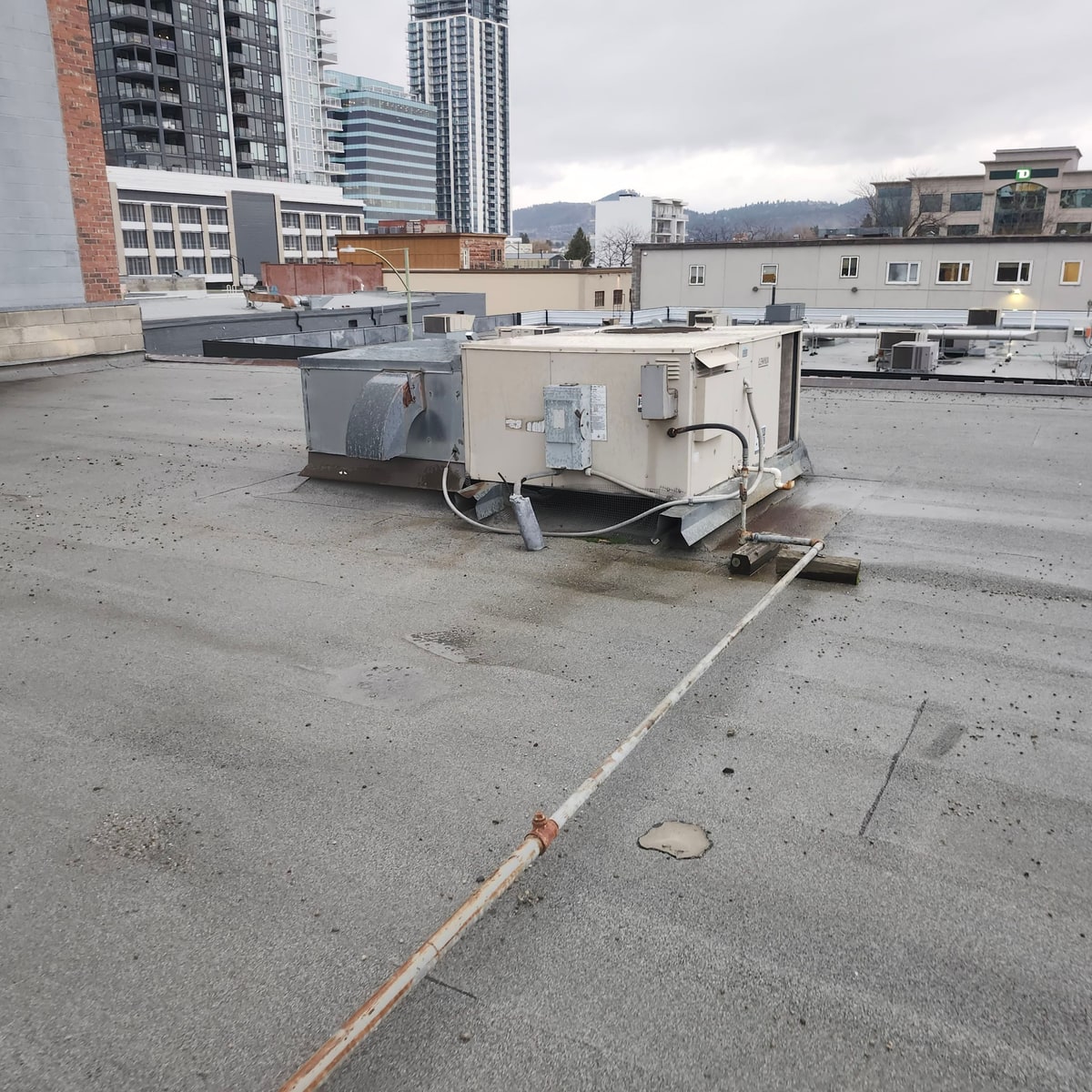 A large rooftop unit sitting on the worn old roof, a stained patch beside it