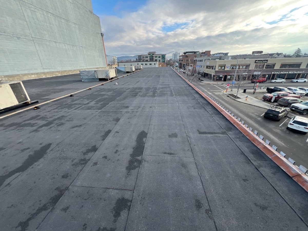 The same street side with the new black torch-on roof, parked cars below
