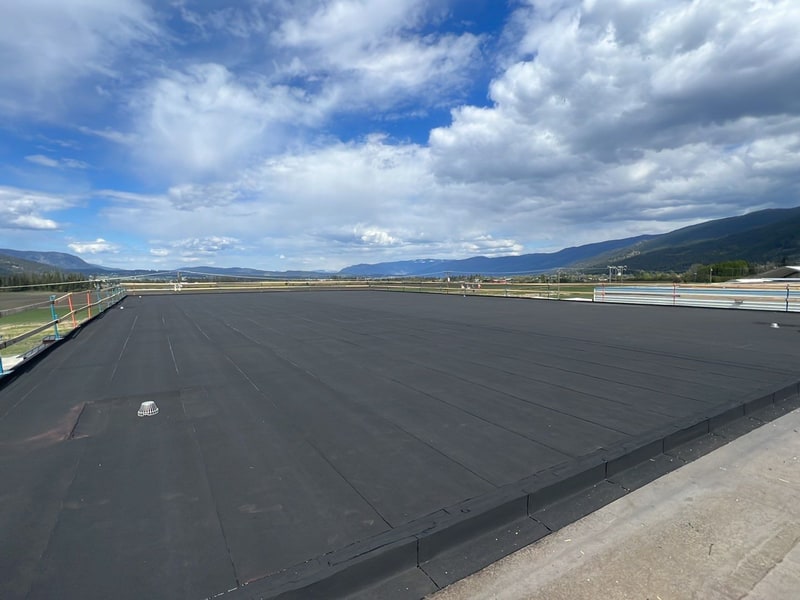 Completed two-ply SBS industrial re-roof with the valley and mountains beyond
