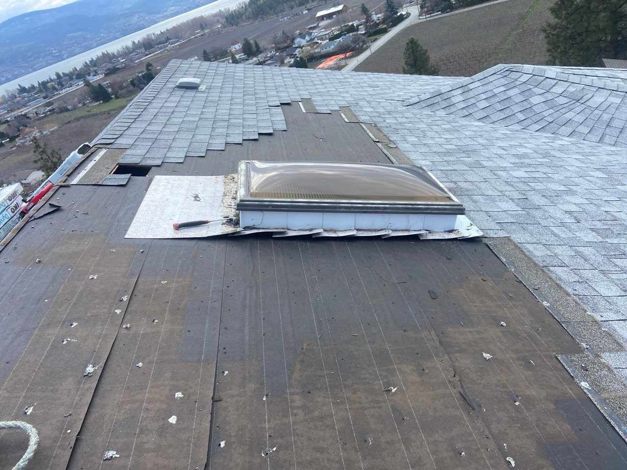 A roof opened up around a skylight during a repair, tools out, lake beyond