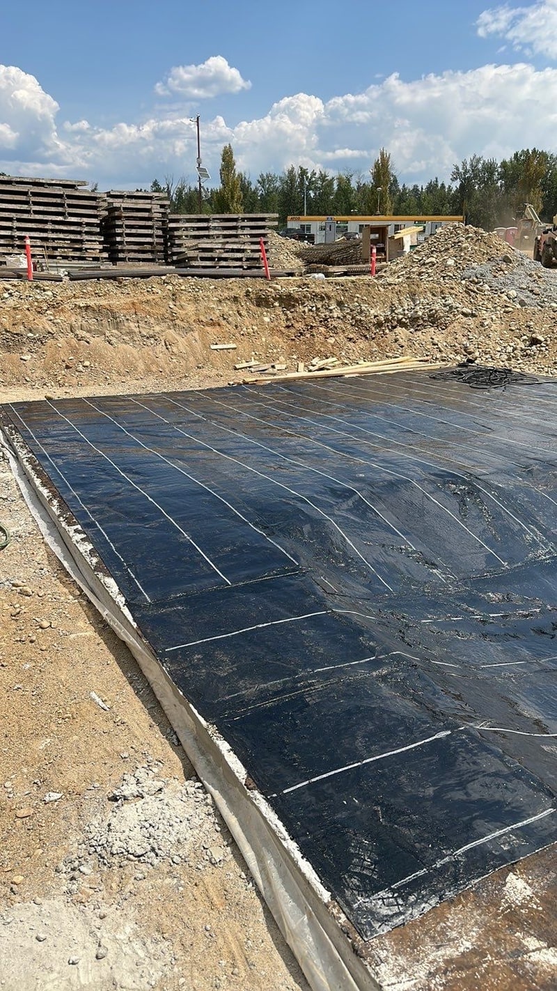 Black membrane laid in overlapping sheets across the floor of an excavation