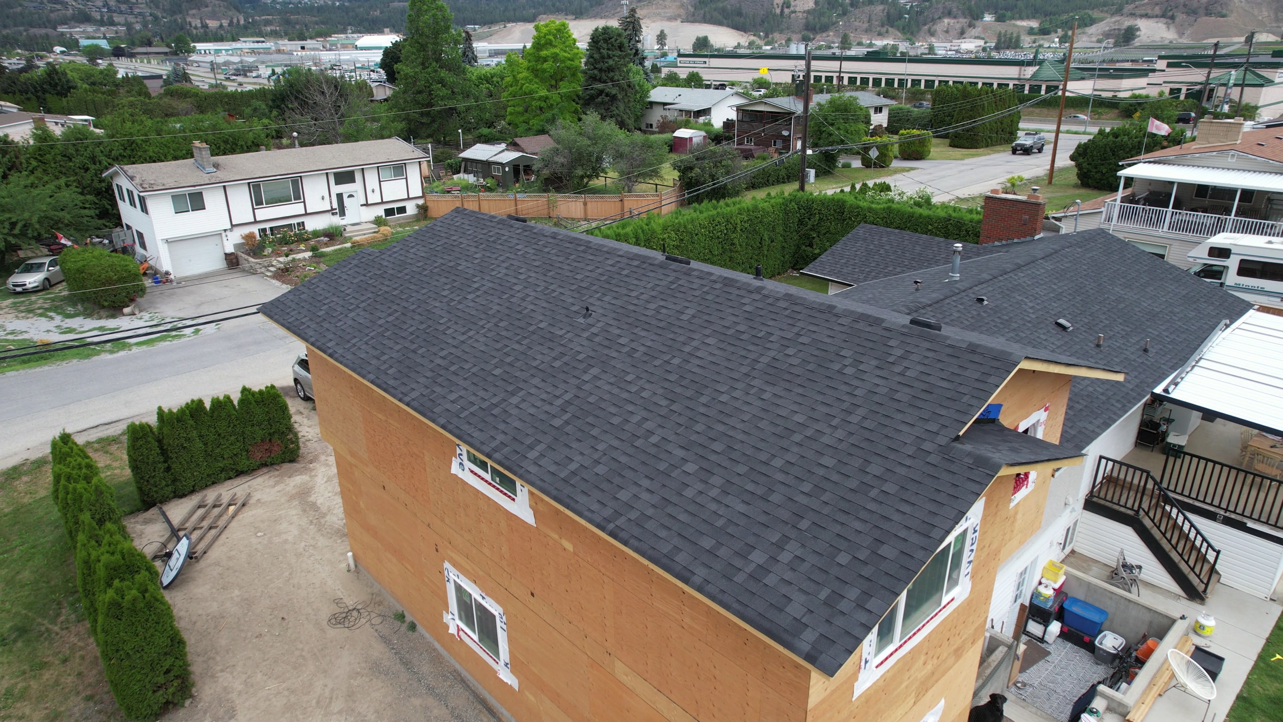 Charcoal shingle roof finished on a new house, its walls still in sheathing
